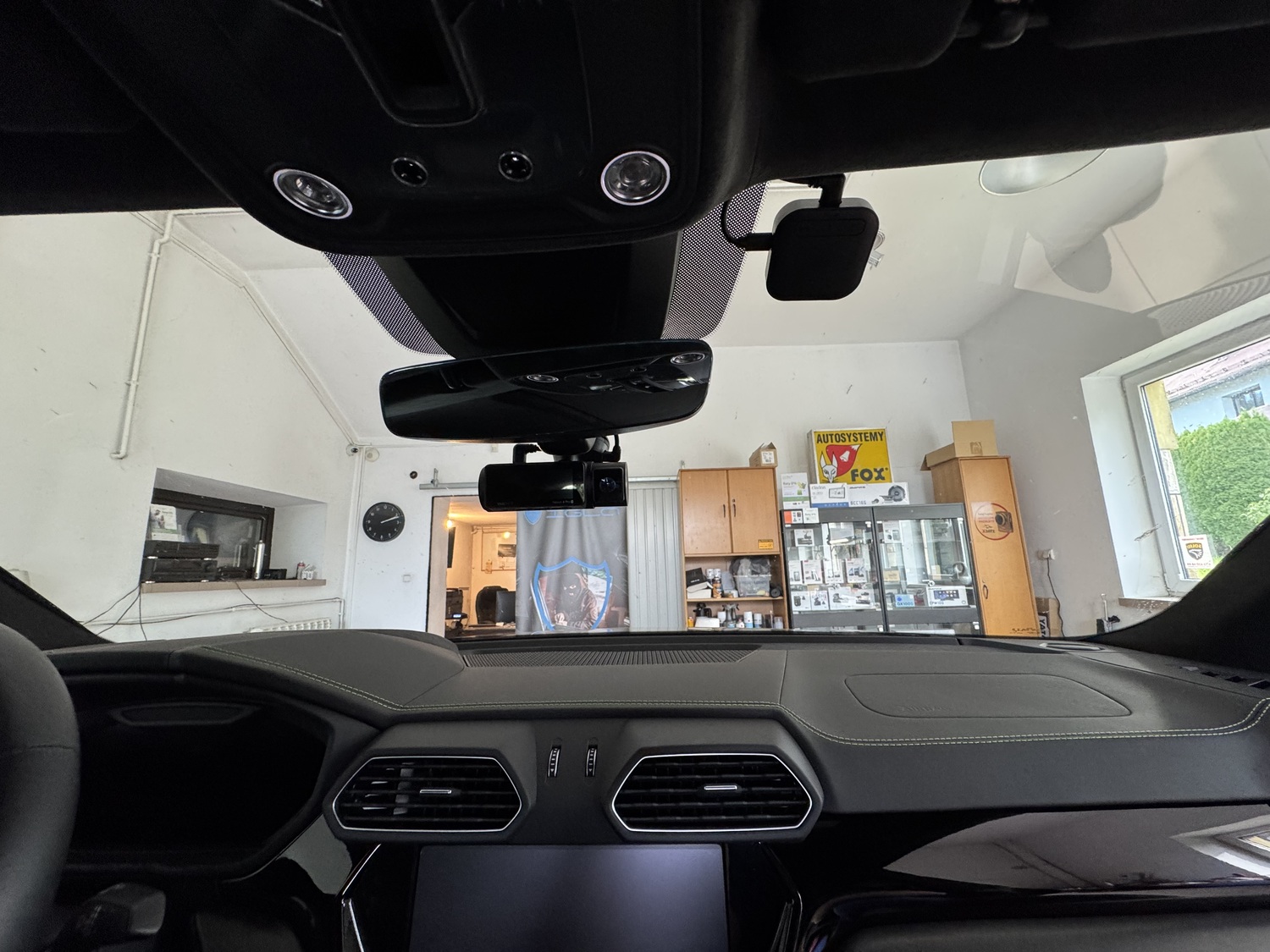 Widok zza kierownicy Lamborghini Urus - kamera Vantrue za lusterkiem i modem LTE 01 przy podsufitce