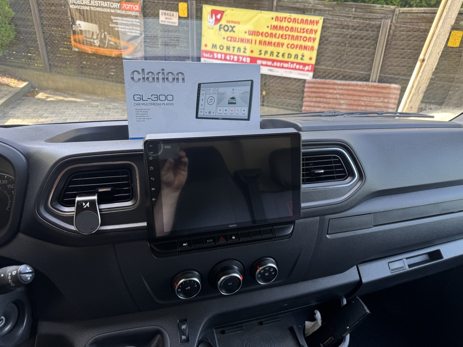 Stacja multimedialna Clarion GL-300 osadzona na desce Renault Master, w tle pudełko stacji
